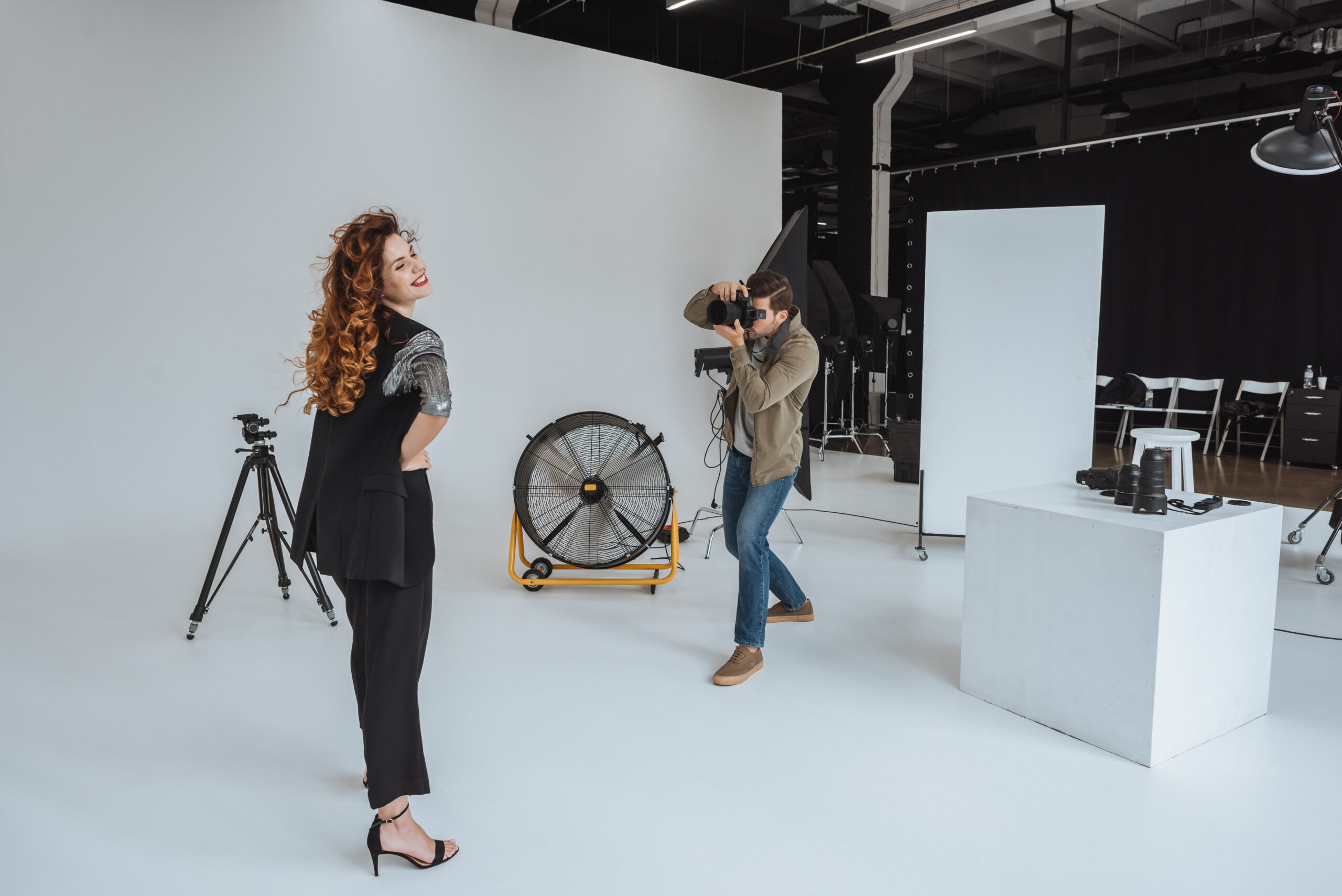 professional photographer and beautiful model on fashion shoot in photo studio with fan